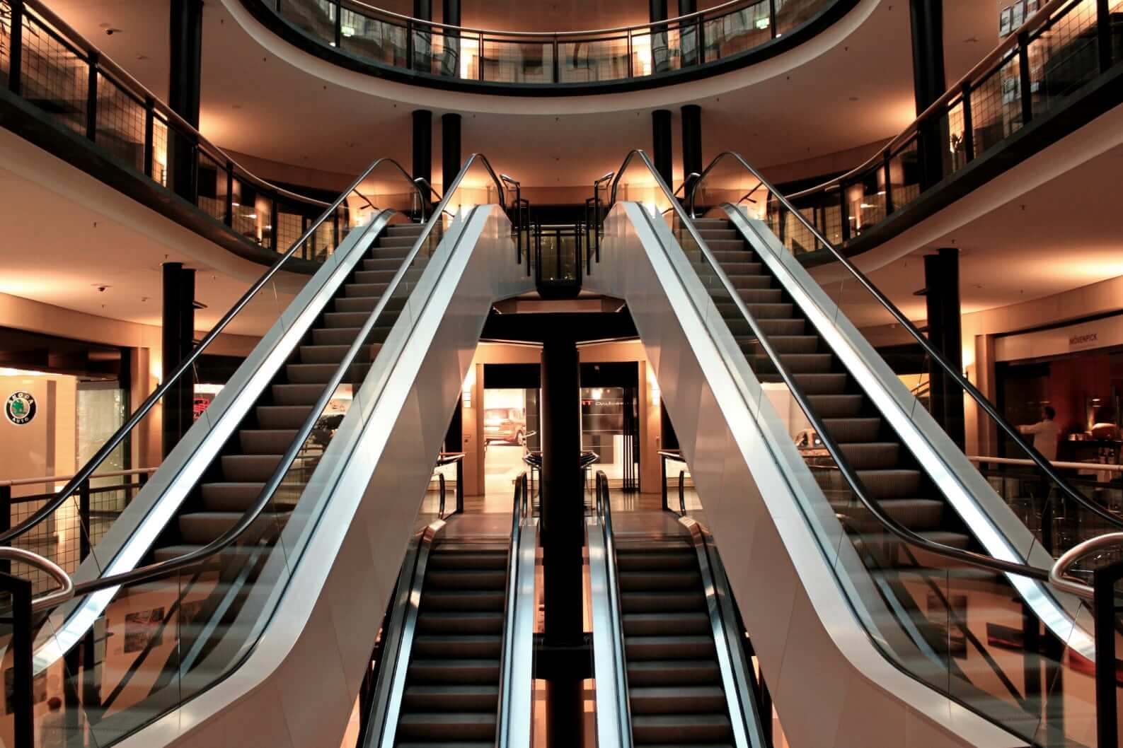 Symmetrical, ominous escalators in an empty mall.