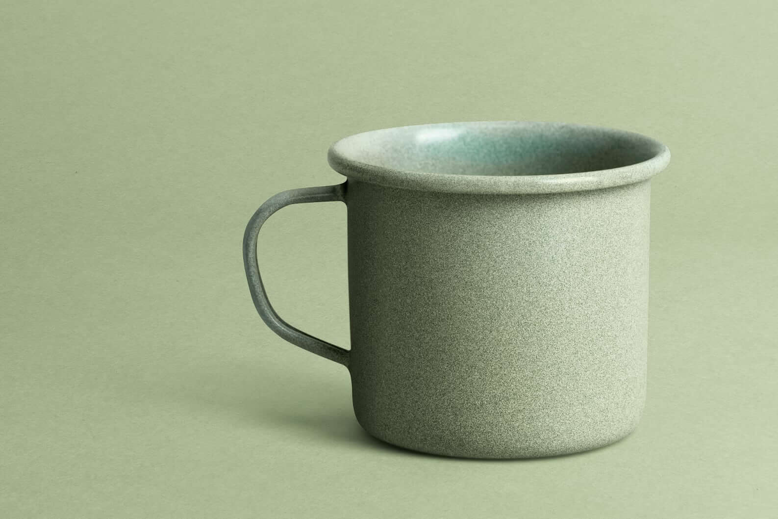 Photo of green speckled ceramic mug on green background