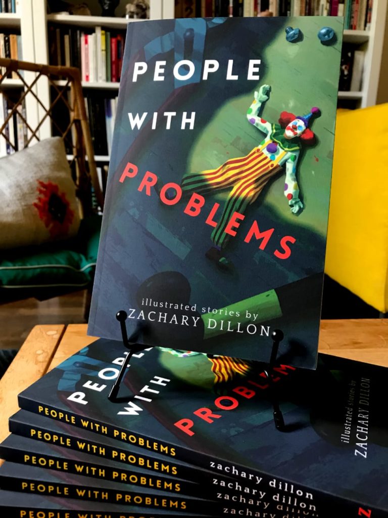 A stack of paperback copies of the book People With Problems with a copy prominently displayed on top, with a living room bookshelf in the background